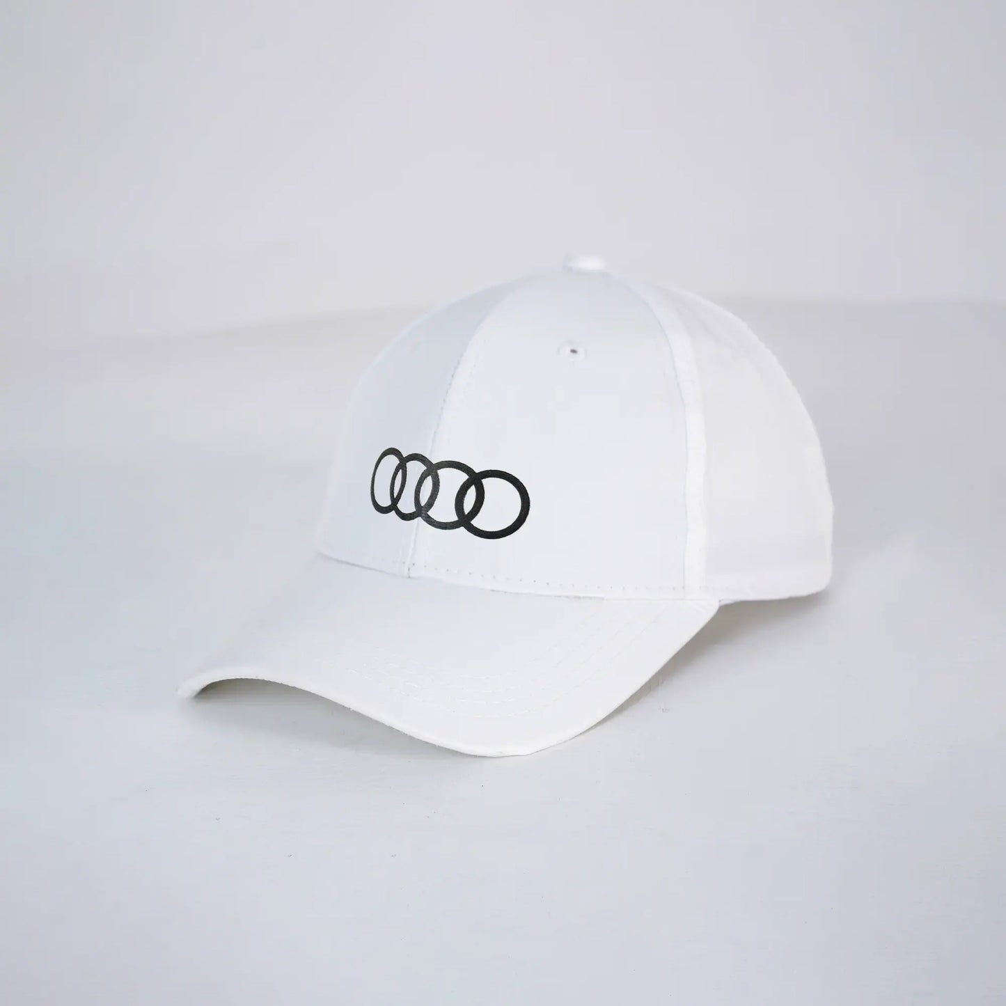 White cap with black Audi logo on a light gray background