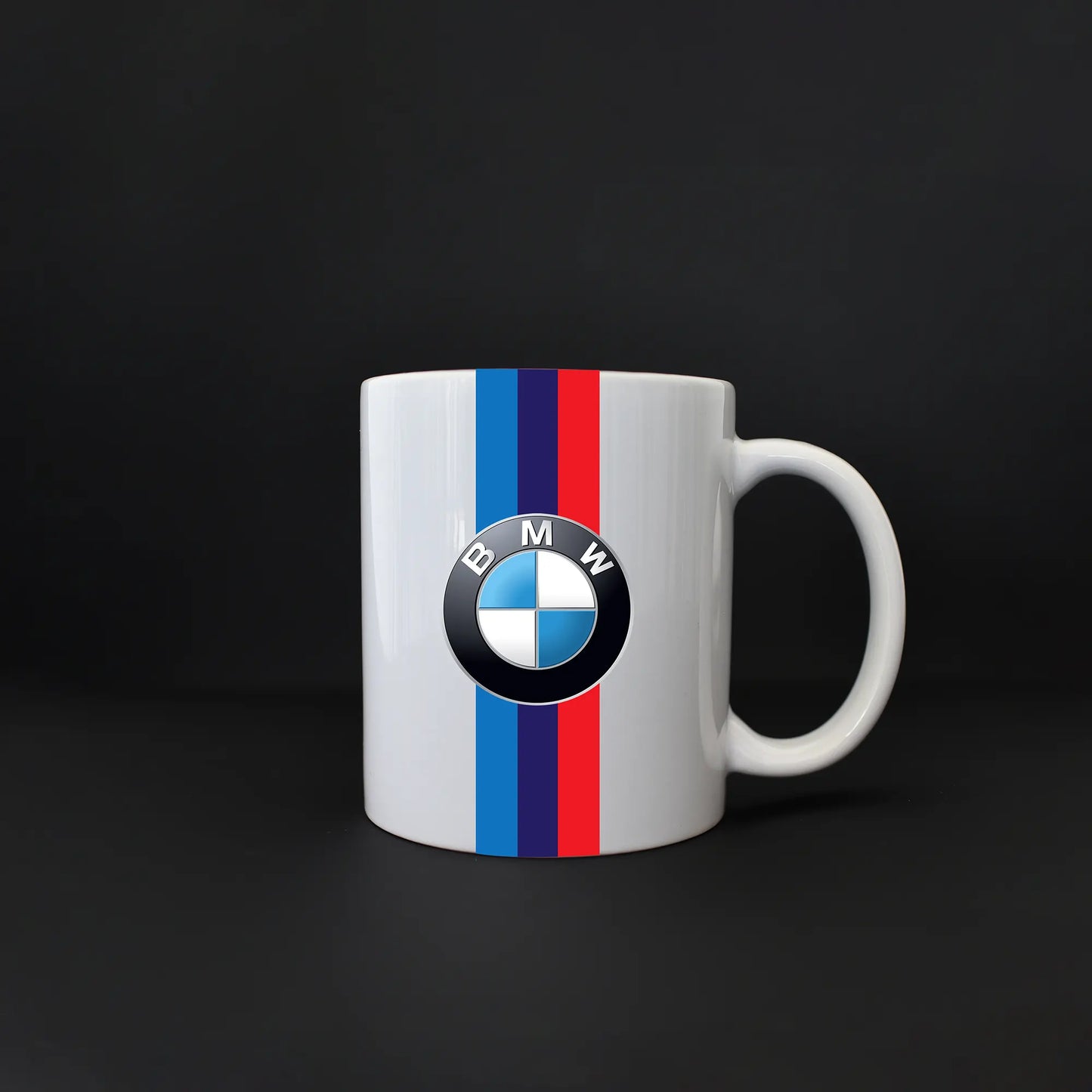 A white ceramic mug with the BMW logo and red, blue, and white stripes on the front.