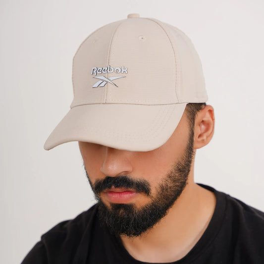 Man wearing a beige Reebok cap against a plain background