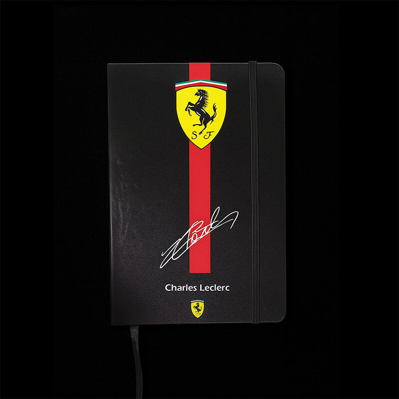 Black notebook with Ferrari logo and Charles Leclerc signature on a black background