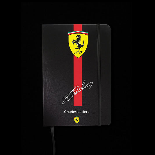 Black notebook with Ferrari logo and Charles Leclerc signature on a black background