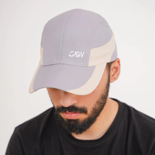 Man wearing a gray and beige cap with a logo on a white background