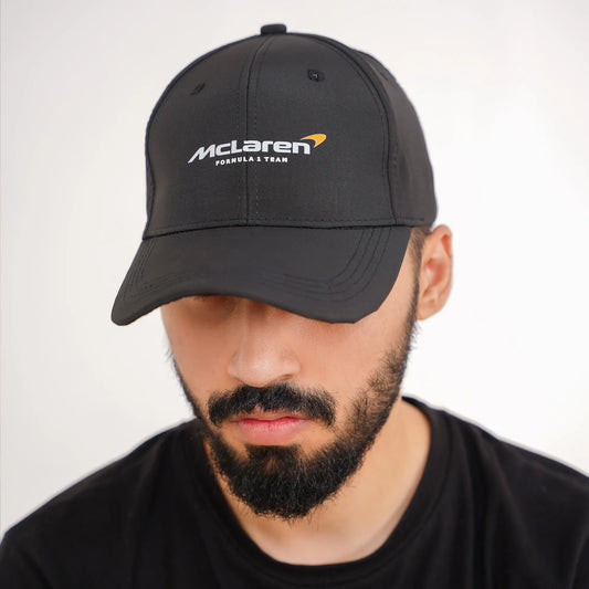 Man wearing a black McLaren cap against a white background