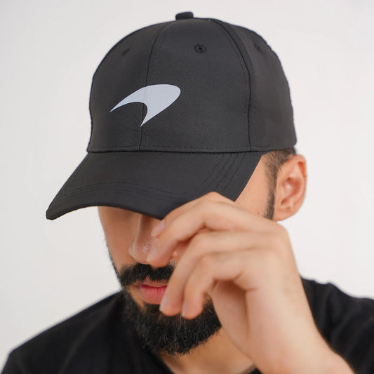 Person wearing a black cap with a logo on a plain background