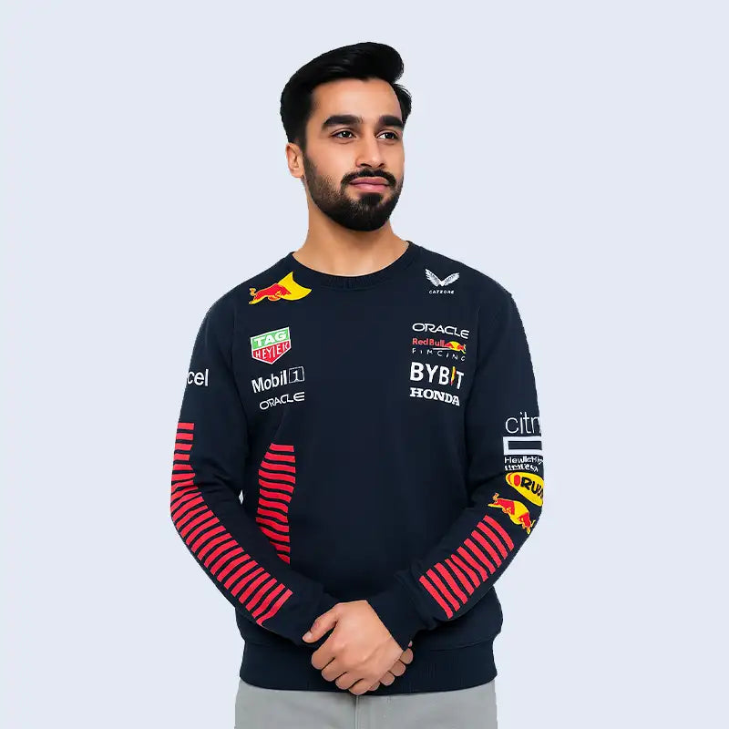 Person wearing a Navy sweatshirt with various sponsor logos on a light gray background