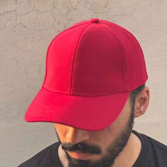 Person wearing a red cap against a textured wall.