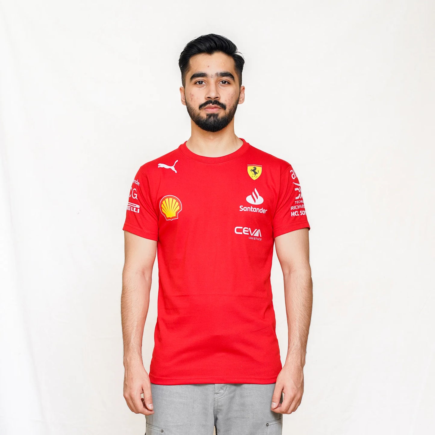 A male model wearing a red Scuderia Ferrari Sainz T-shirt with short sleeves, a classic crew neckline, and logos on the front and back.