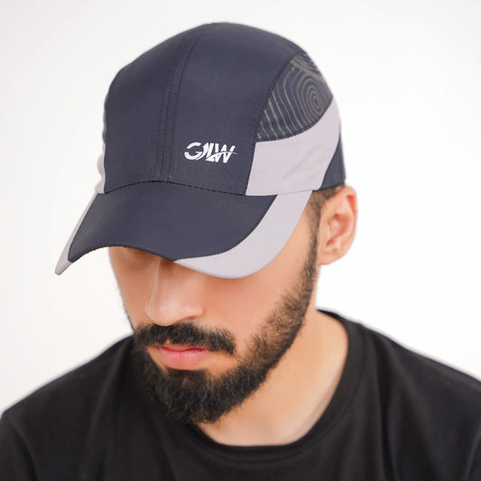 Man wearing a navy and gray cap with a logo on a white background