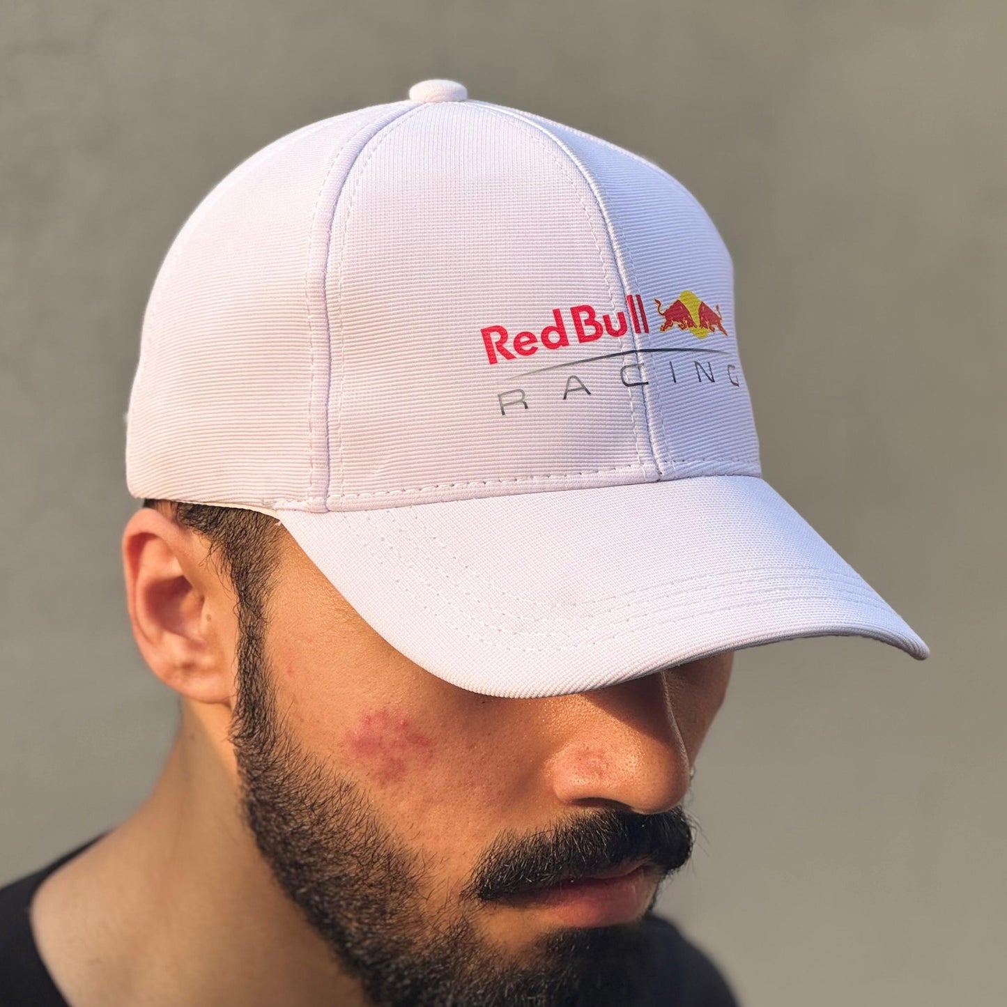 Person wearing a white cap with a logo against a plain background