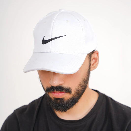 Man wearing a white Nike cap with a black logo on a plain background