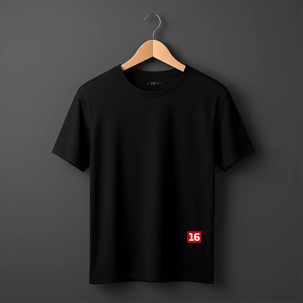 A black short-sleeve crewneck t-shirt hanging on a wooden hanger against a dark gray background. The shirt features a small red square graphic on the lower right side containing the white number '16'.