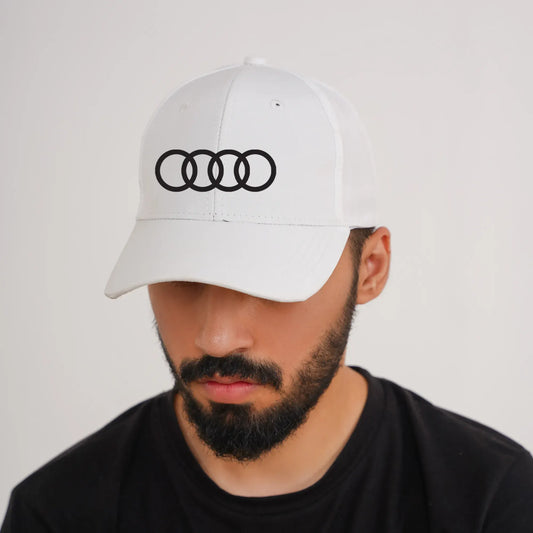 Man wearing a white cap with an Audi logo on a plain background