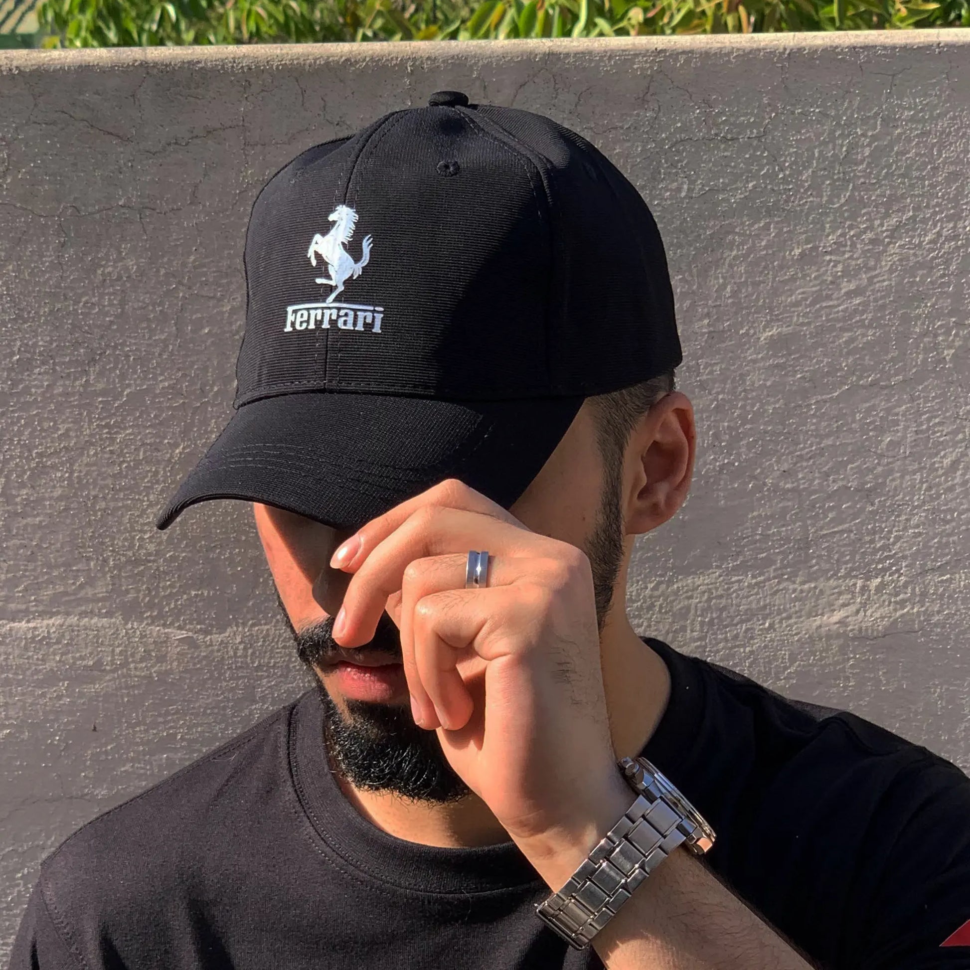 Person wearing a black Ferrari cap against a gray wall