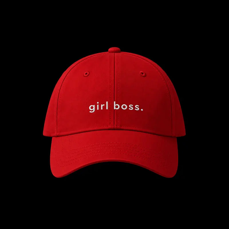 A red baseball cap with the phrase 'girl boss.' embroidered in white lowercase letters on the front, shown against a solid black background.