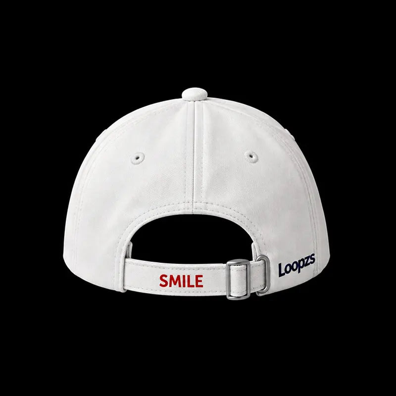 White baseball cap shown from the back, featuring a white adjustable strap with a silver metal buckle. The strap is printed with the word 'SMILE' in red on the left and 'Loopzs' in black on the right.