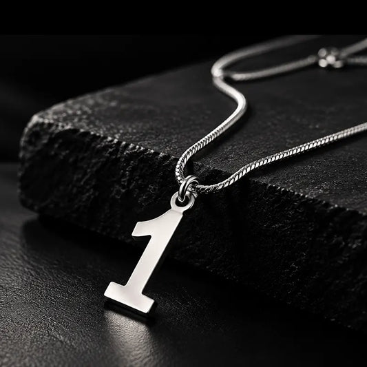 Silver number 1 pendant on a snake chain resting on black stone