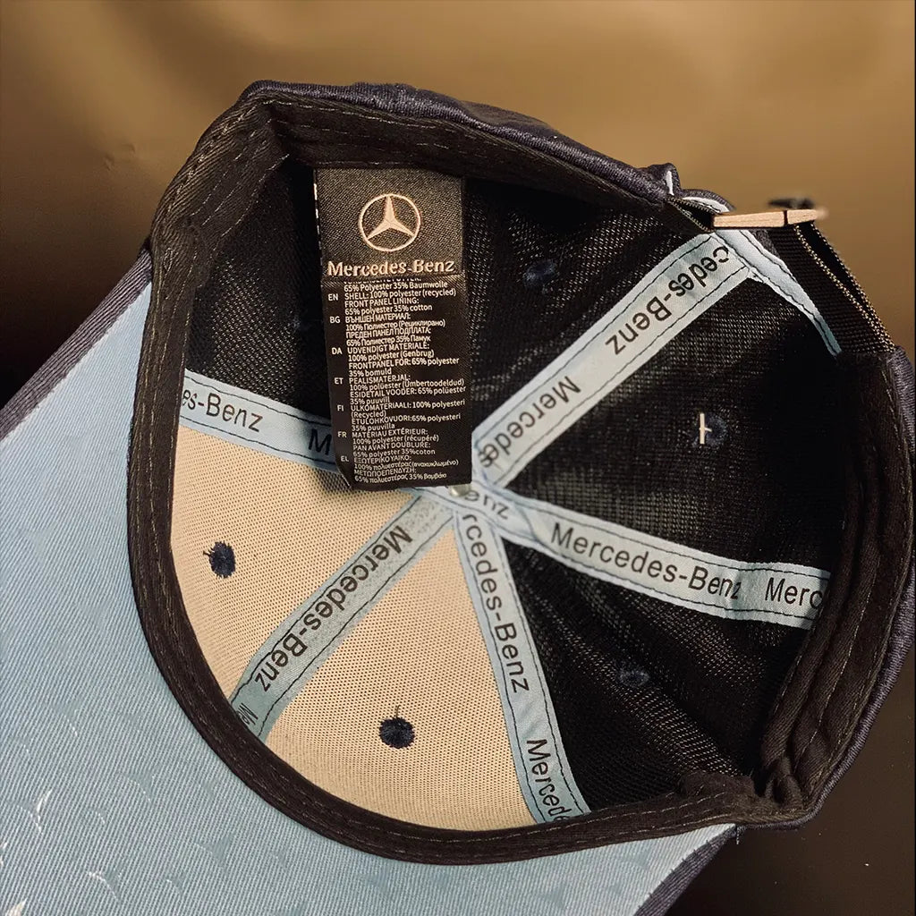 Black cap with Racing Collection-Benz logo and text on a brown background