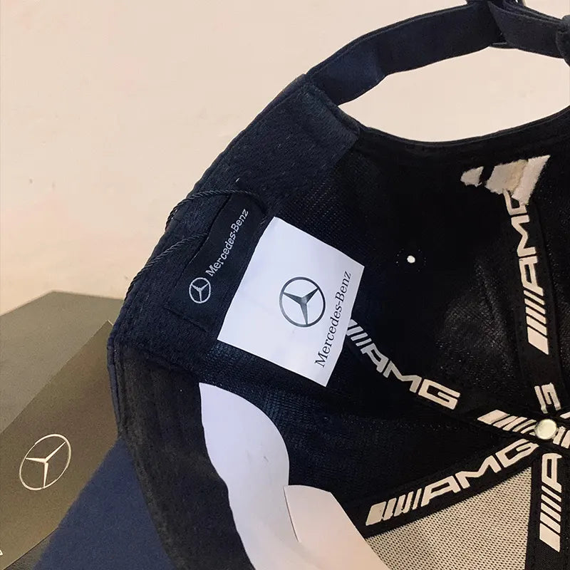 Black cap with Mercedes-Benz and AMG logos on a beige background