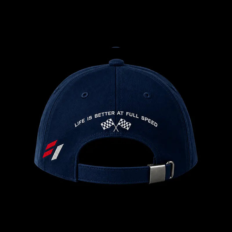 A navy blue baseball cap shown from the back, featuring white embroidered text that reads 'LIFE IS BETTER AT FULL SPEED' above two crossed checkered flags. A small red and white graphic is embroidered on the side, and the cap has an adjustable strap with a silver metal buckle, all set against a solid black background.