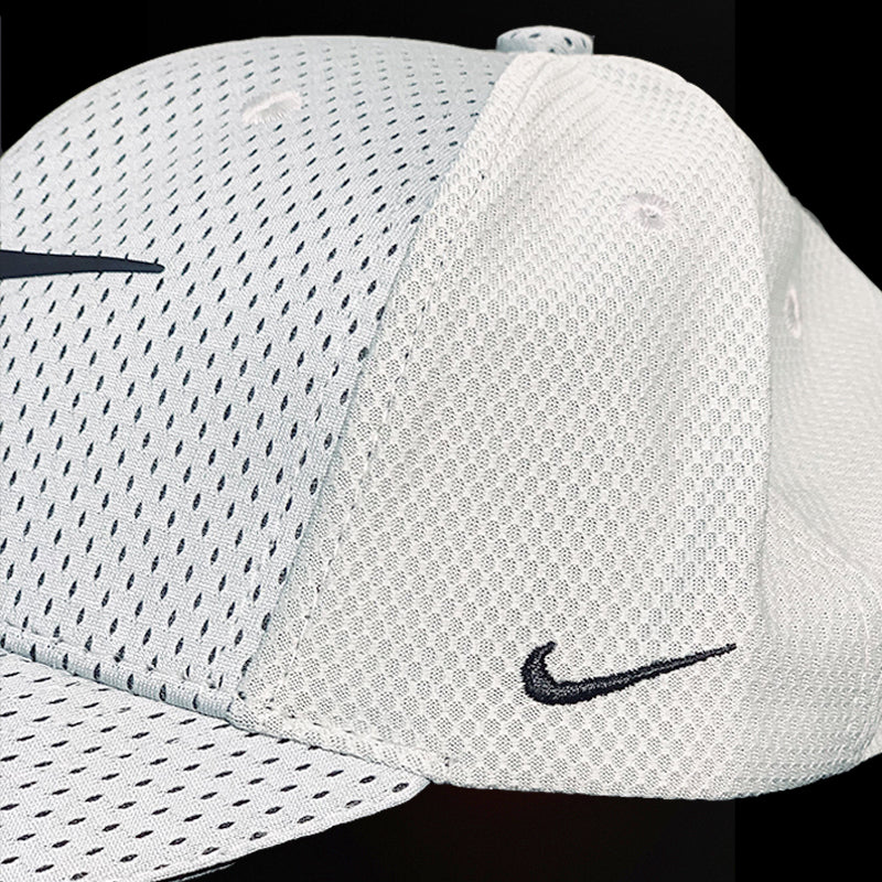 White Nike cap with black swoosh logo on a black background
