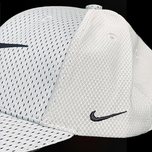 White Nike cap with black swoosh logo on a black background