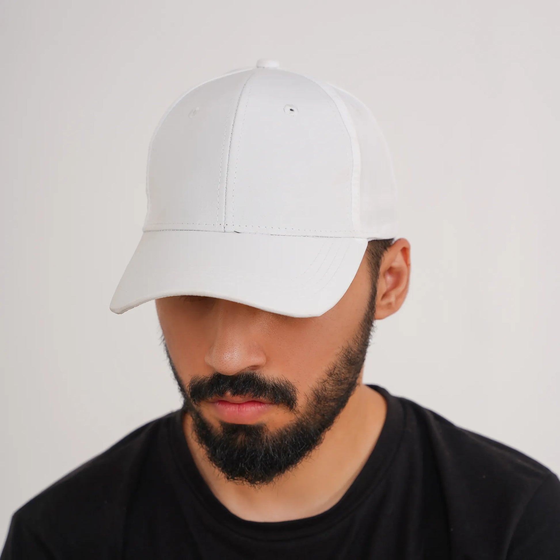 Man wearing a white cap and black shirt on a light gray background
