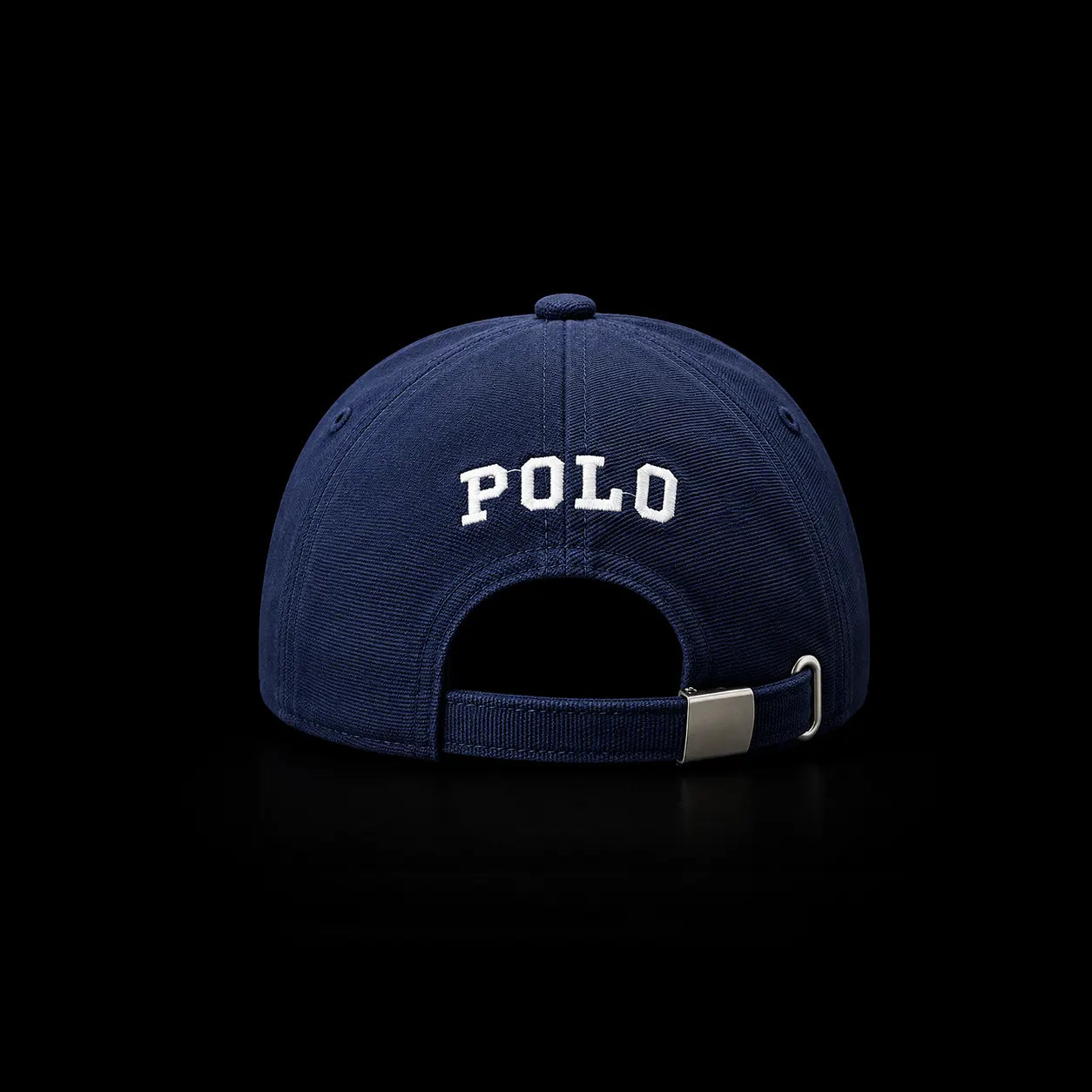 A navy blue Polo brand baseball cap shown from the back, featuring white embroidered 'POLO' lettering and an adjustable snapback strap with a silver metal buckle, set against a solid black background.