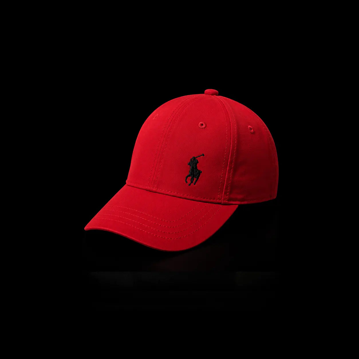 A red baseball cap with a black embroidered Polo Ralph Lauren pony logo on the front, photographed against a solid black background.
