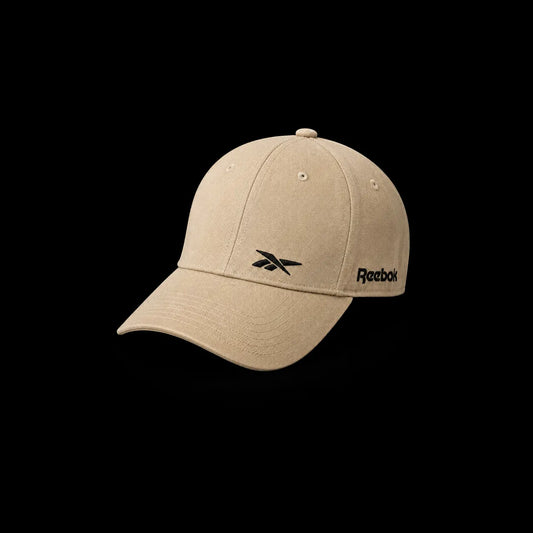A beige Reebok baseball cap with a black embroidered logo on the front and side, shown against a solid black background.