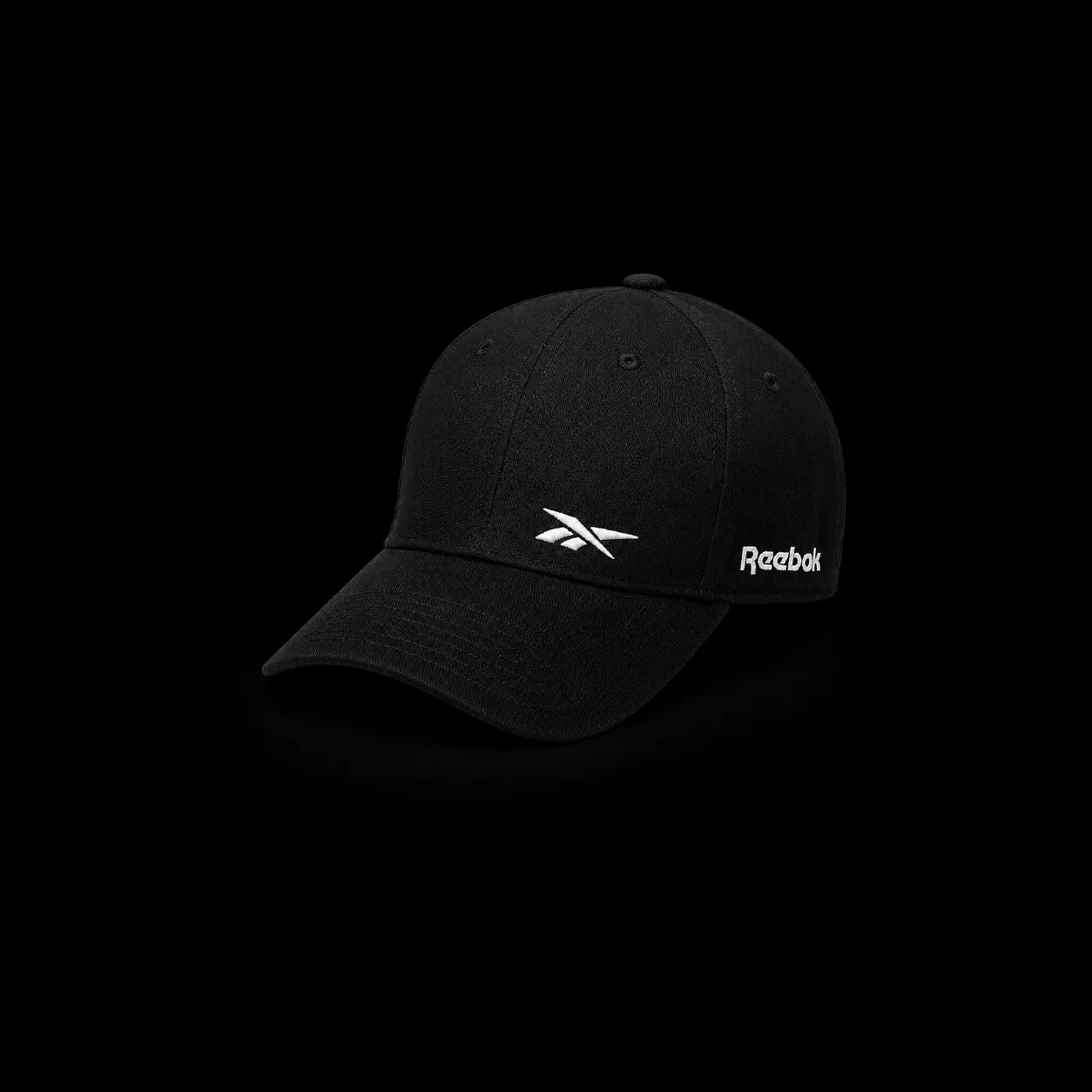 A black Reebok baseball cap with a white embroidered logo on the front and side, shown against a solid black background.