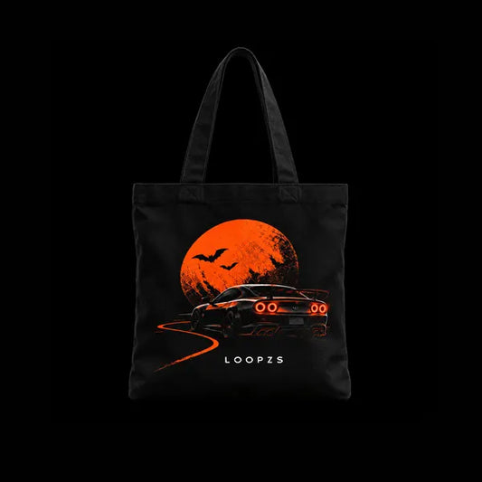 Black tote bag with orange moon, bats and a sports car with glowing red tail lights on a winding road, Loopzs Halloween print