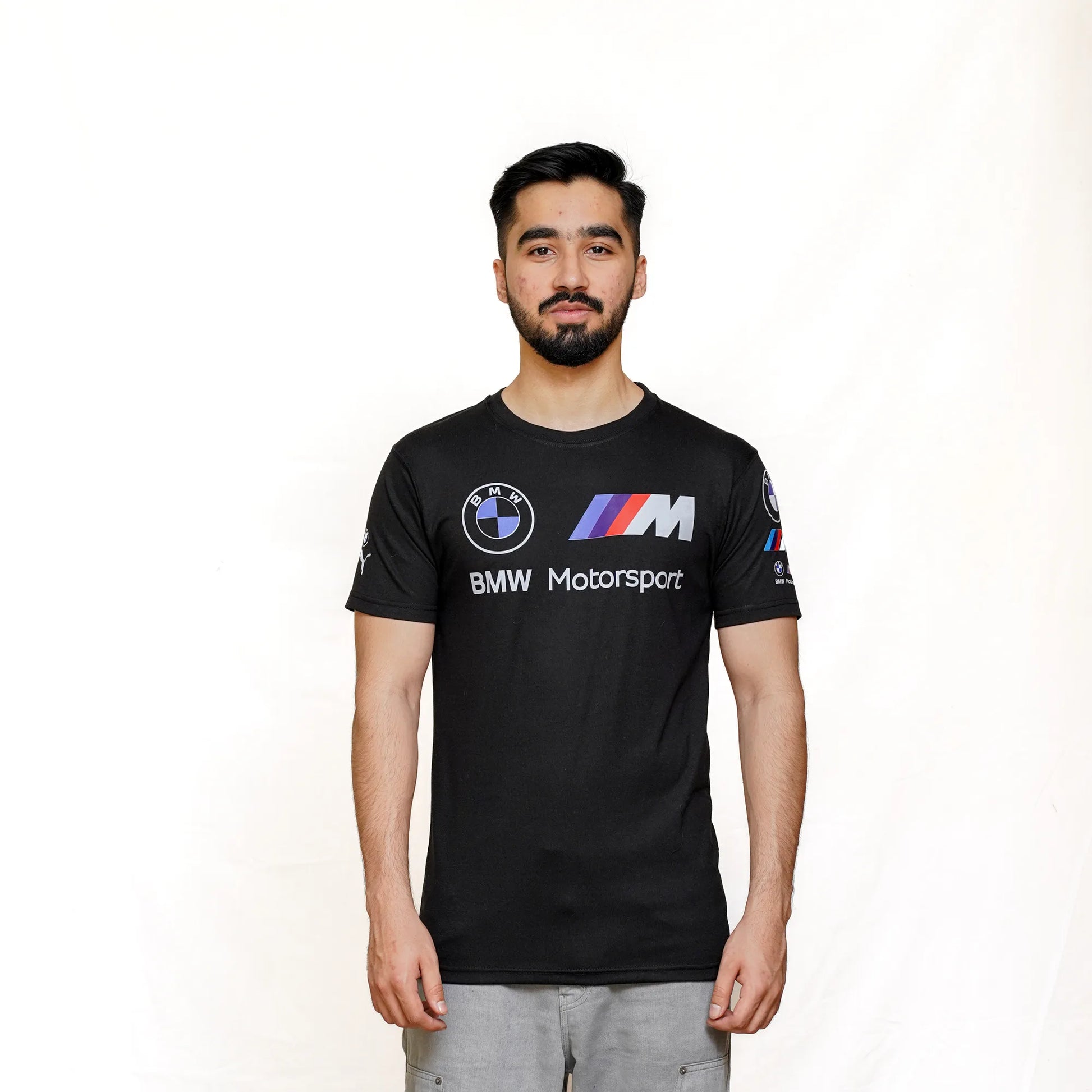 A male model wearing a black BMW M Motorsport logo T-shirt with short sleeves and a classic crew neckline.