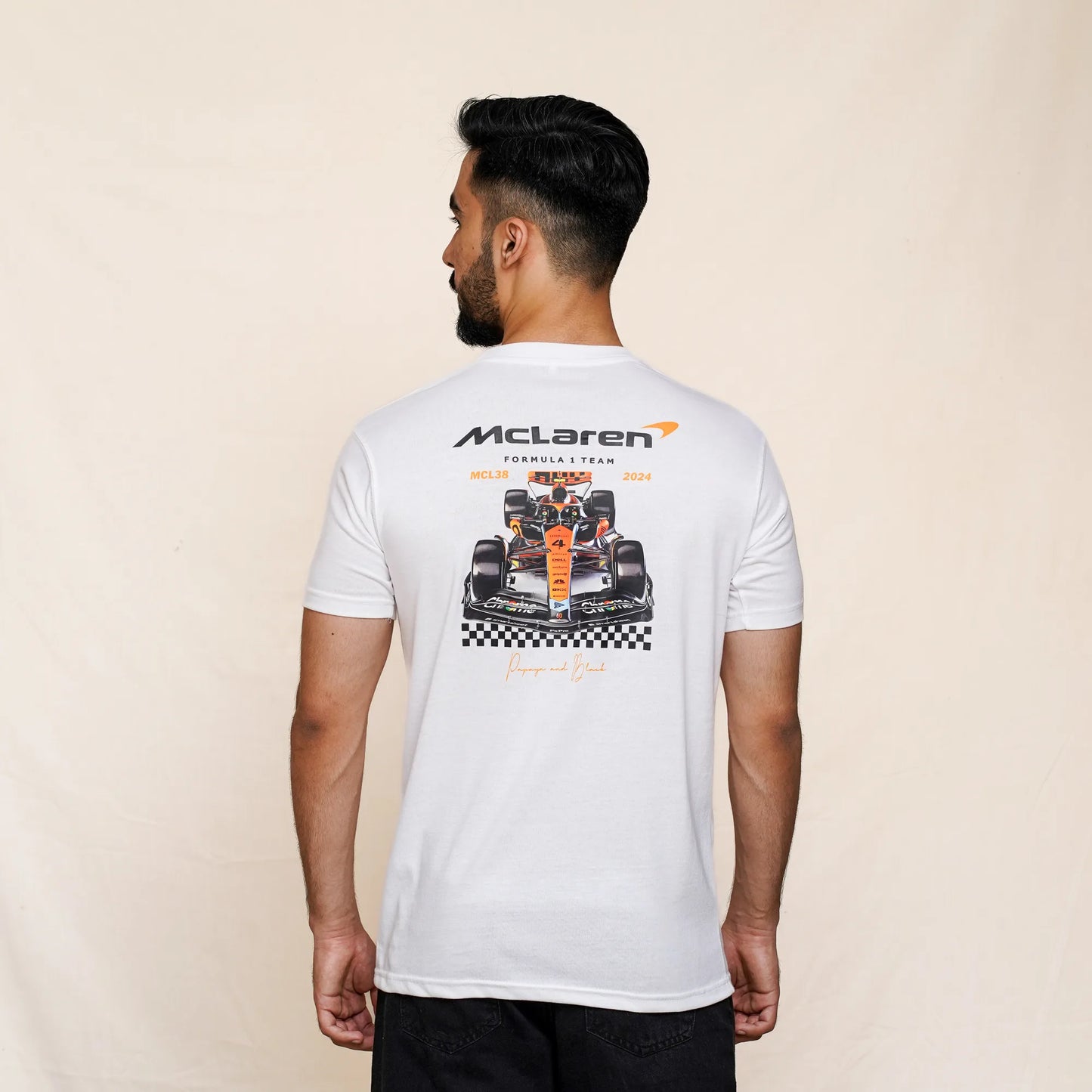A man wearing a white McLaren F1 t-shirt with graphics and text on the back.