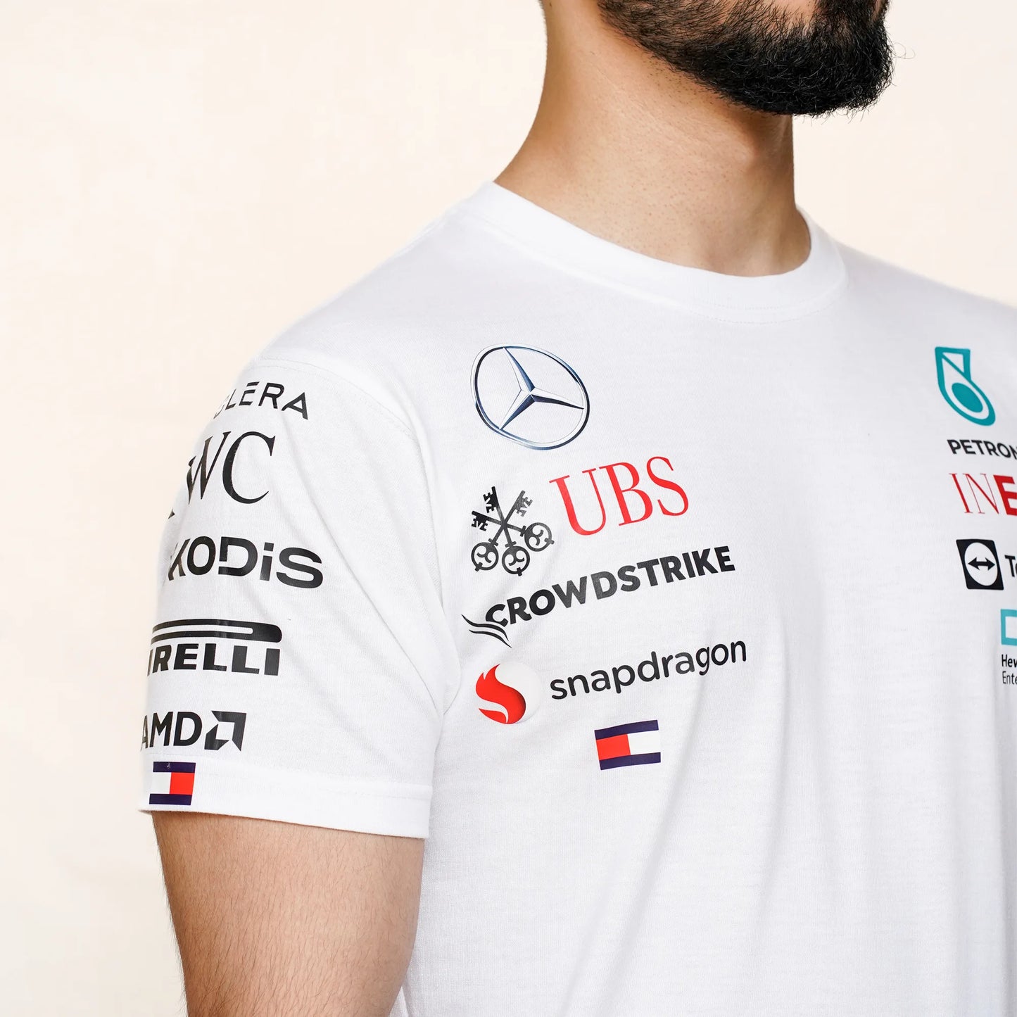 Men’s white Formula-style team T-shirt with multicolor logos, photographed from the front.